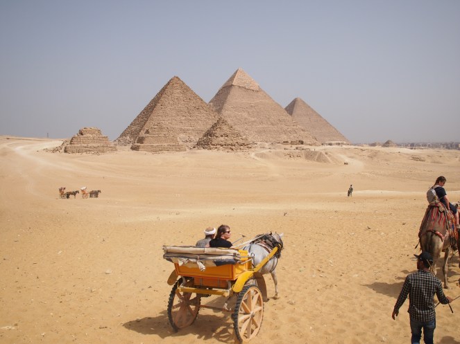 Image showing the Pyramids of Giza, with a horse-drawn carriage and camels in the foreground