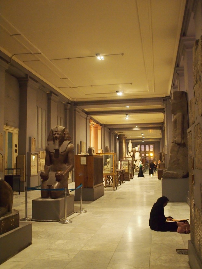 Photograph showing the interior of the museum; a long gallery with statues and glass cases
